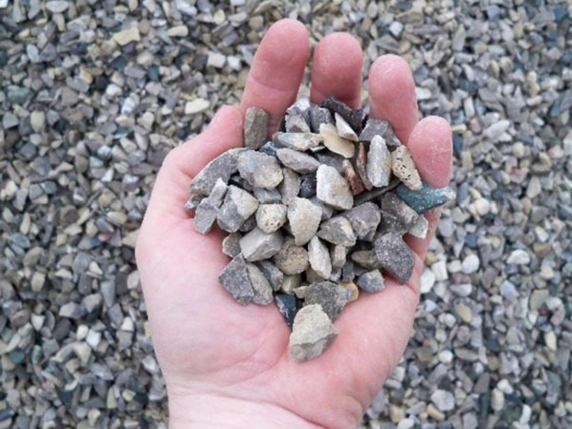 a person is holding a pile of gravel in their hand .