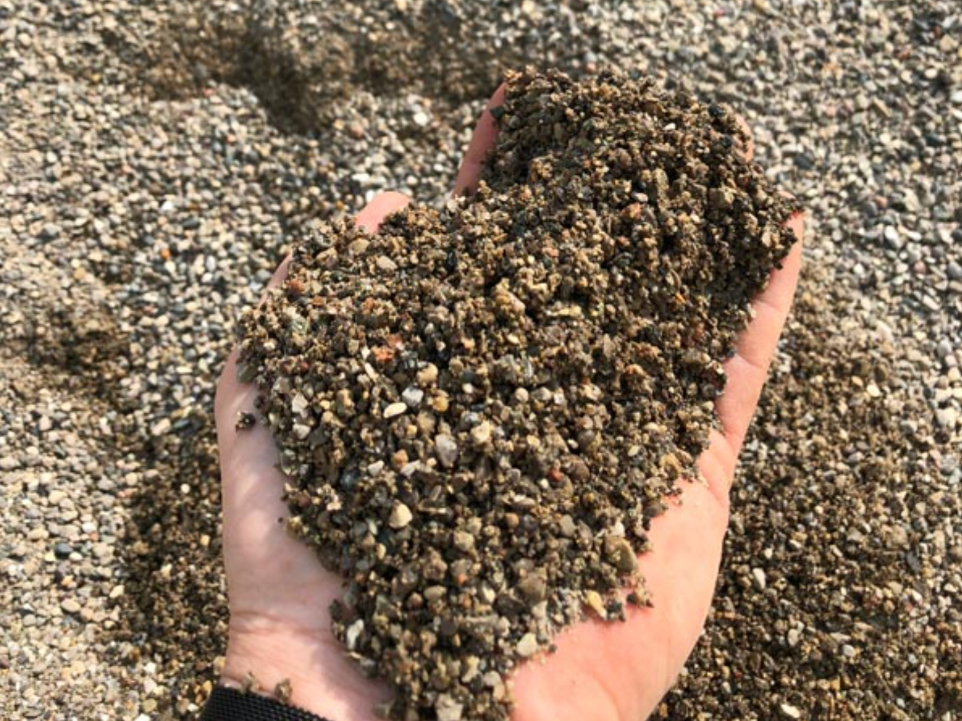 a person is holding a pile of gravel in their hand .