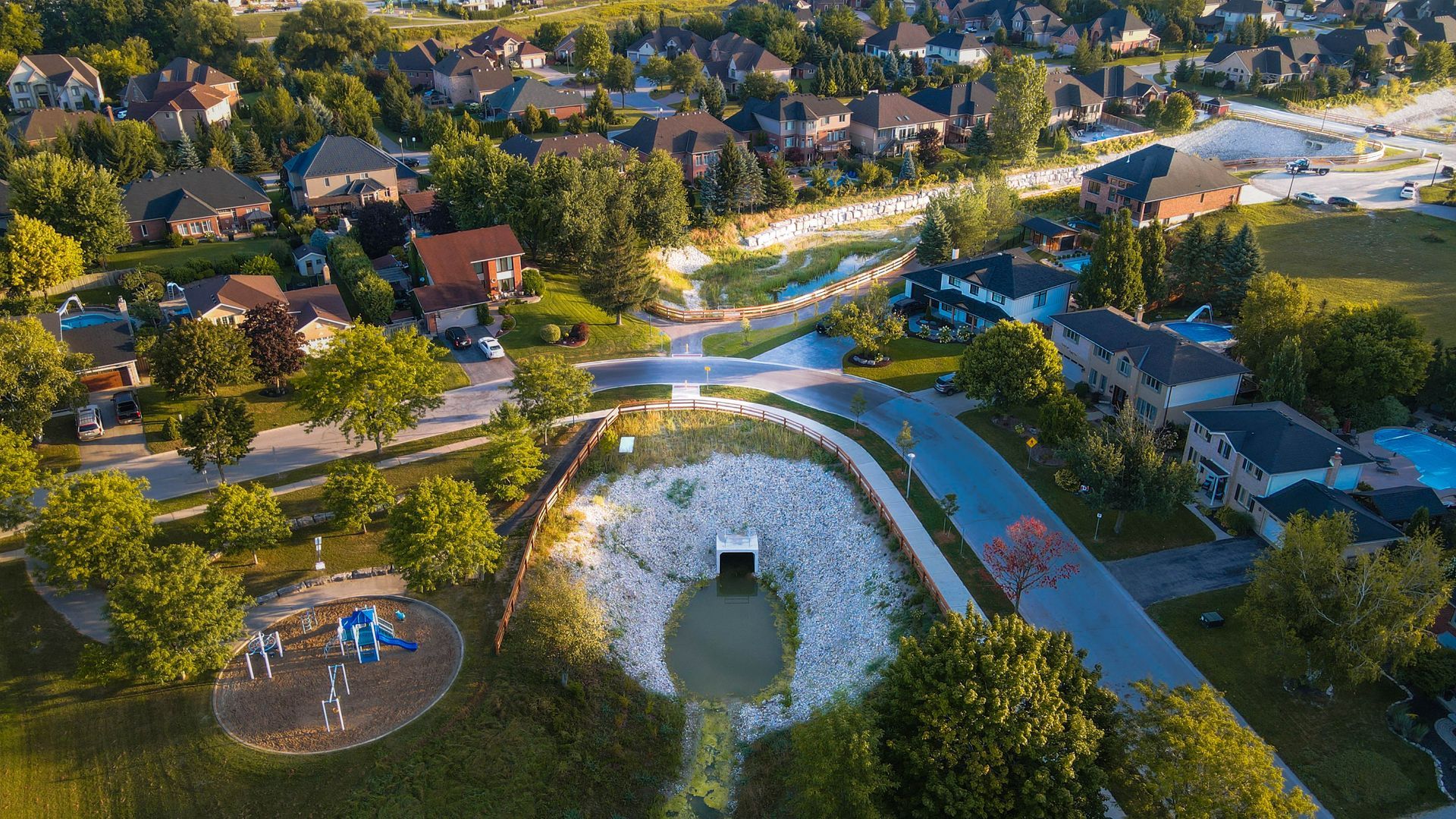 An aerial view of a residential area with a pond and a playground.