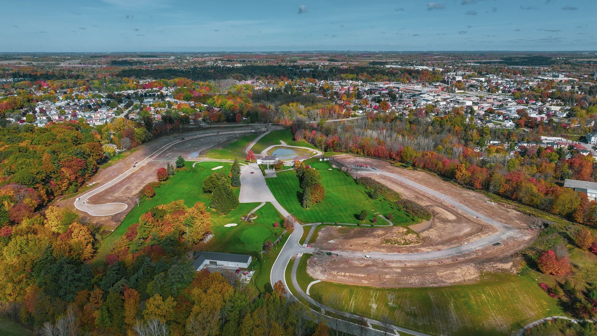An aerial view of a residential area surrounded by trees and a city.