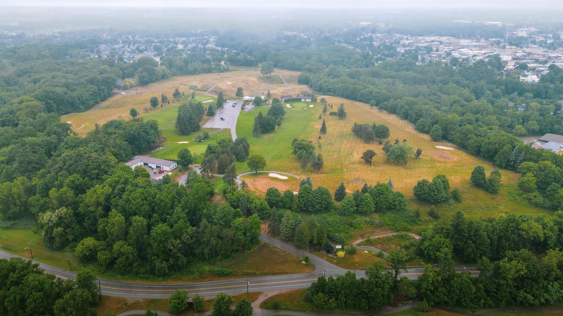 An aerial view of a golf course surrounded by trees and grass.