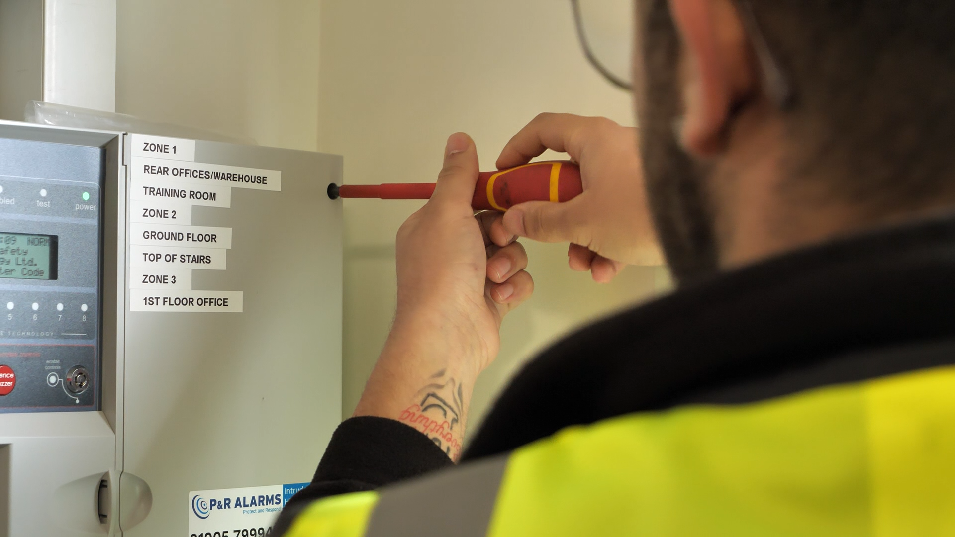 Person in blue uniform writing on a clipboard, possibly conducting an inspection.
