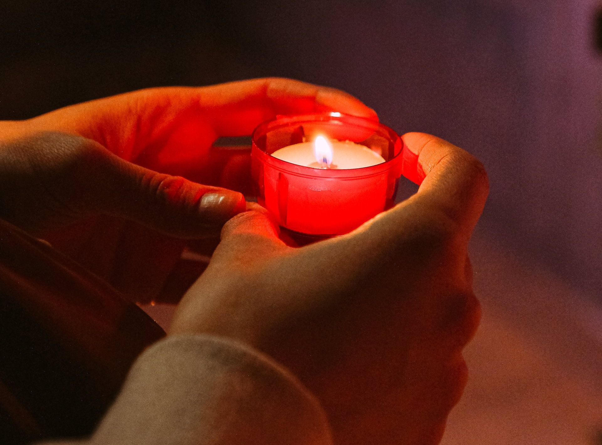 two hands holding a small candle