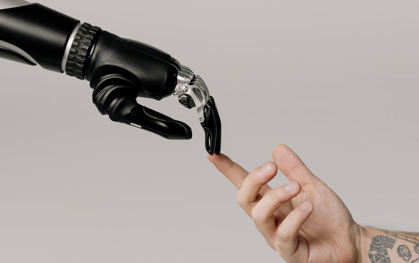 picture of human hand touching black metallic hand of robot