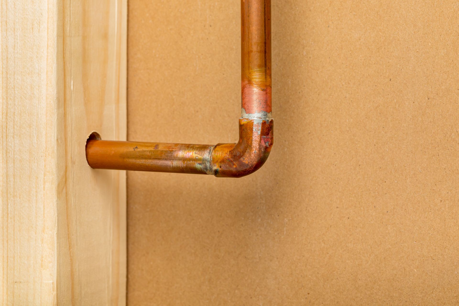 Copper pipe bends, connected to the wall and wooden frame.