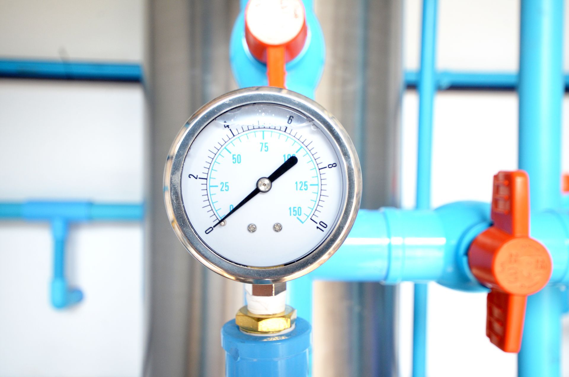 Pressure gauge on blue pipes, showing a pressure reading of around 8.
