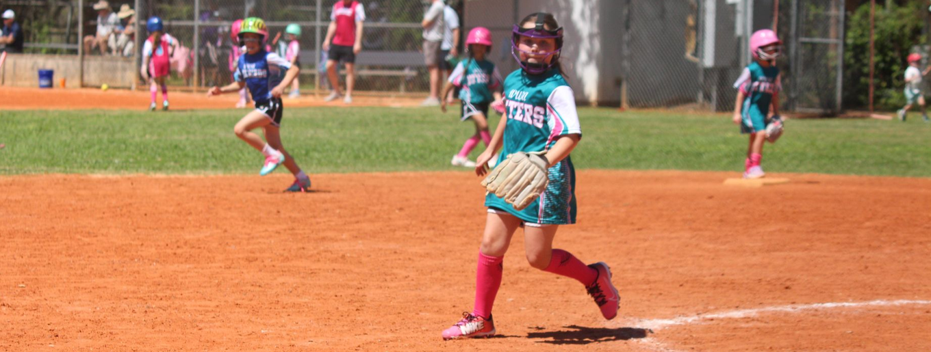 6U Softball game with pitcher fielding the ball.