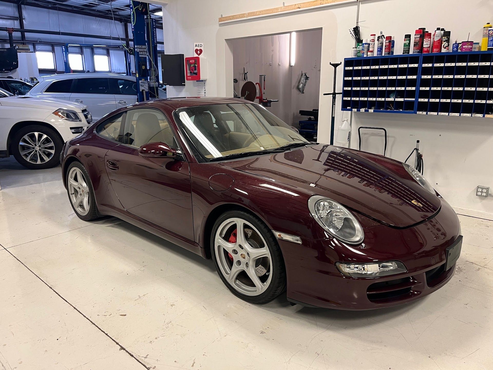 Burgundy Porsche sports car in a garage with a white floor. | Hill Country European Autoworks