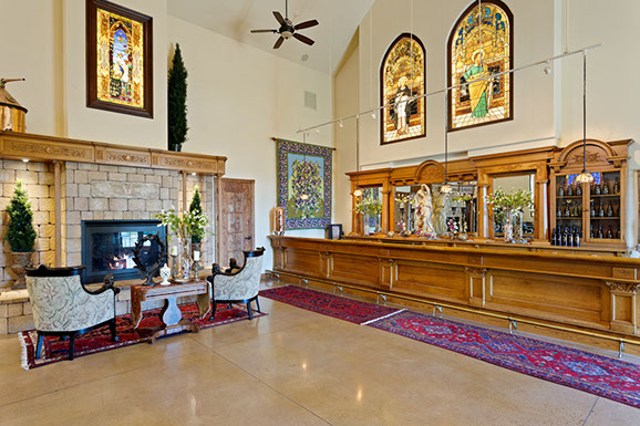 A large room with a fireplace , chairs , and a long wooden counter.