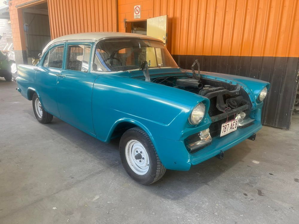 A Blue Car With The Hood Up Is Parked In Front Of An Orange Building — ABS Repairs in Manunda, QLD