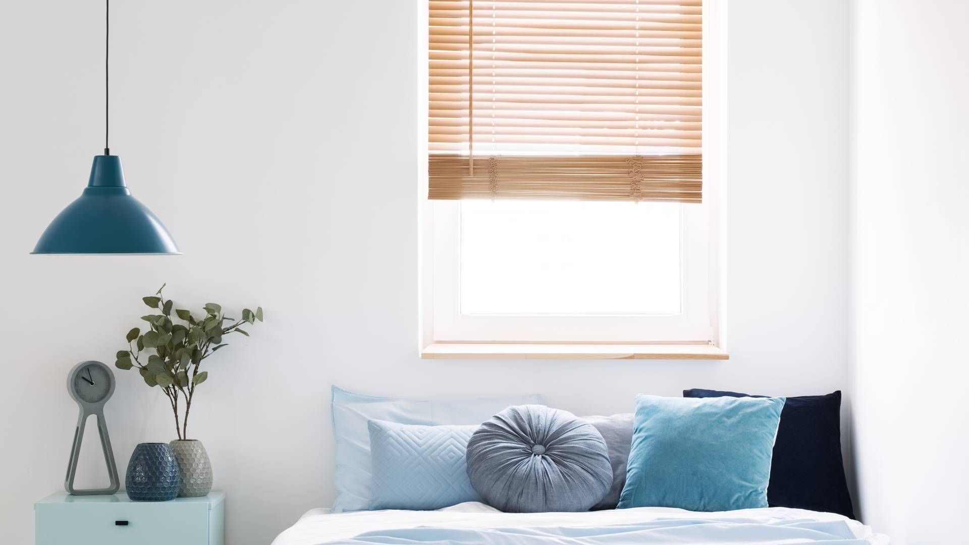 A bedroom with light blue decor and new window blinds at Blinded by Delight Window Coverings & Desig