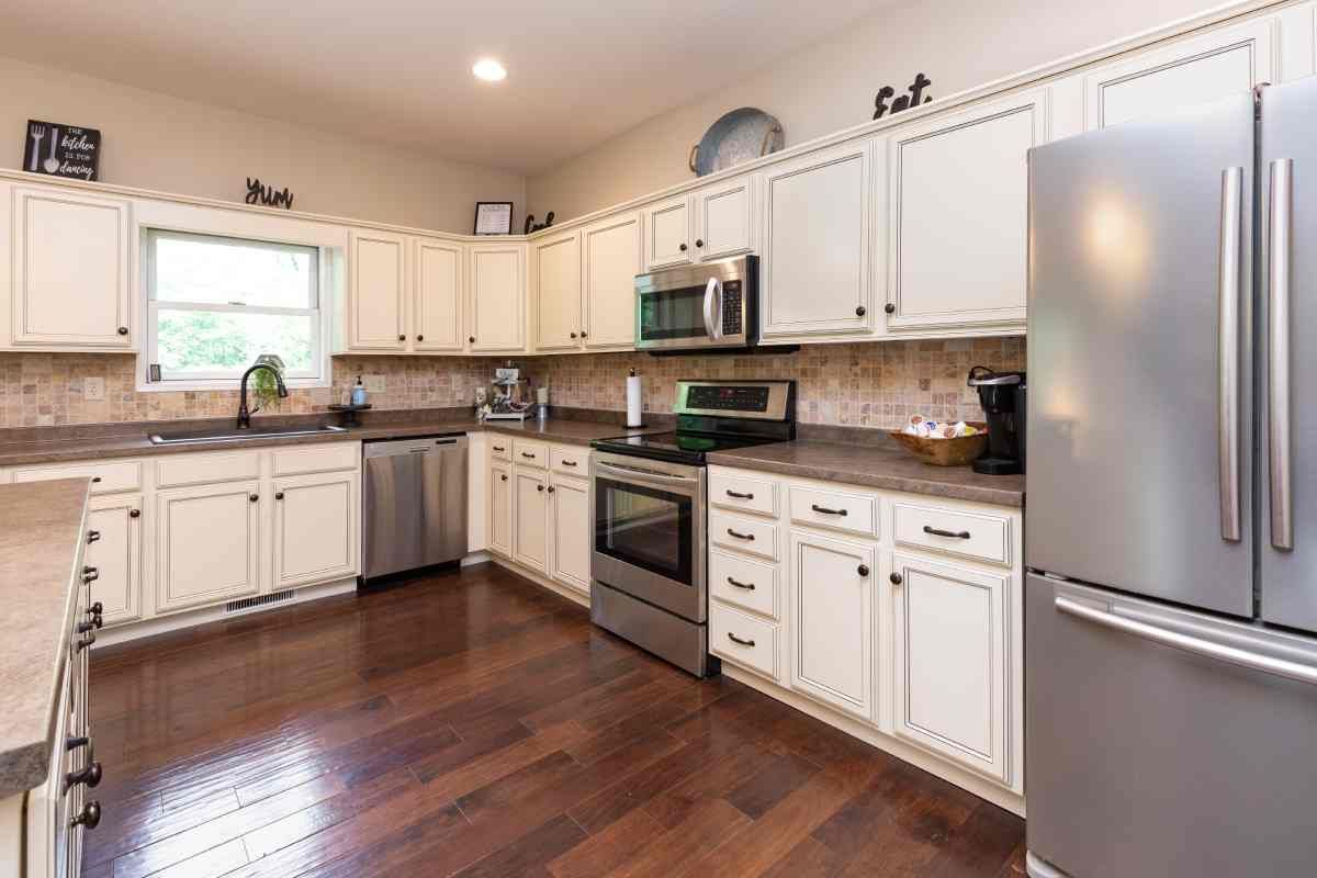  A sizable kitchen with white cabinets, wood floors, and a window at Blinded by Delight Window Coverings & Design near San Antonio and Boerne, Texas (TX)