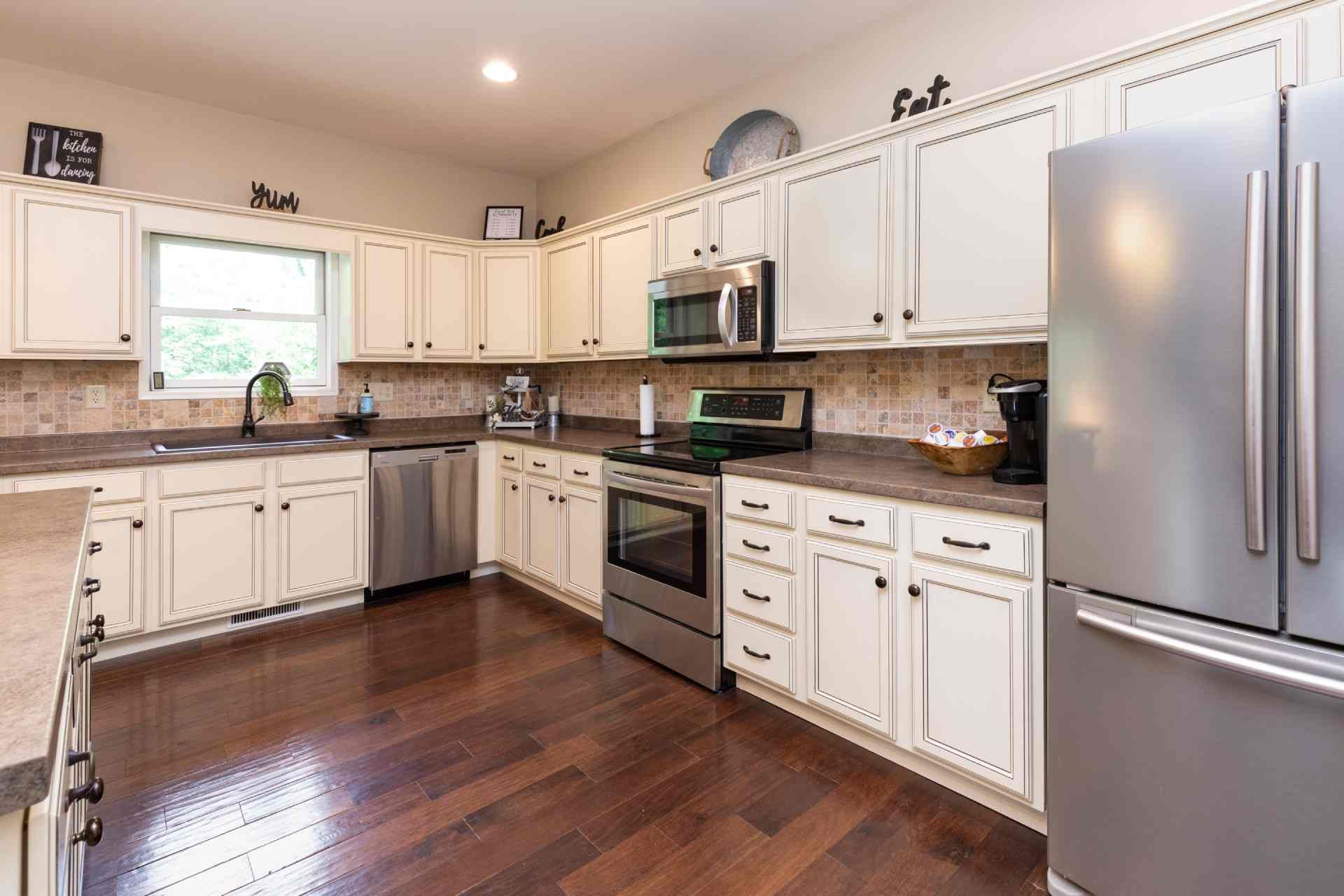  A sizable kitchen with white cabinets, wood floors, and a window near San Antonio and Boerne, Texas