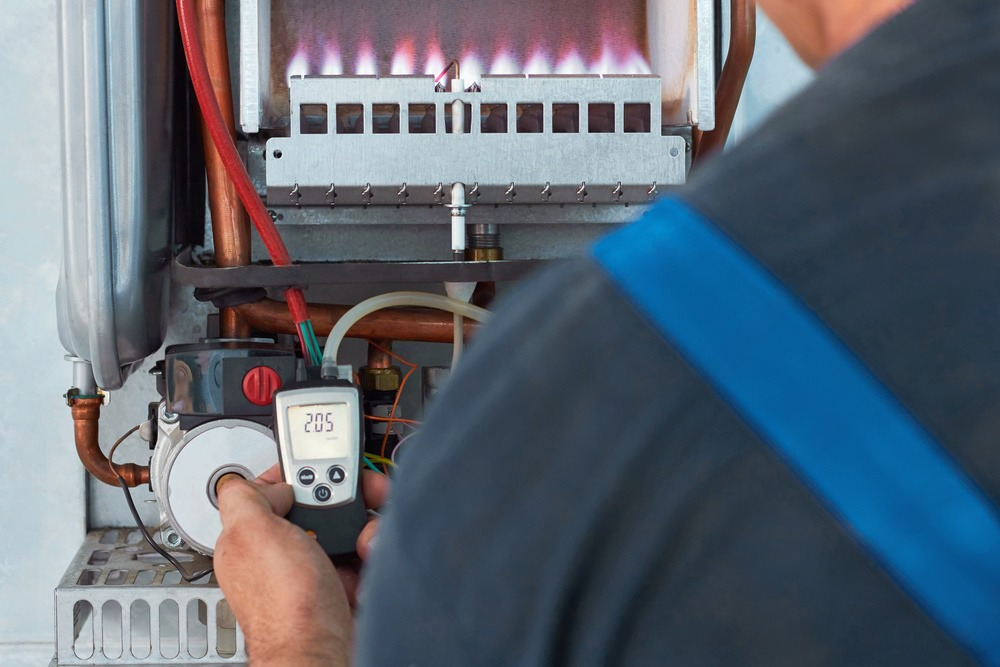 a man is working on a boiler with a digital thermometer .