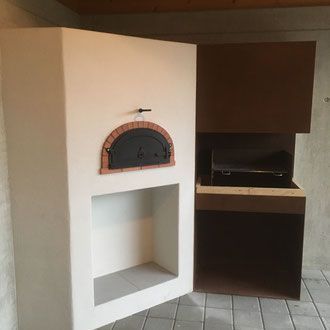 Kombinierter Pizzaofen und Grill für den Außenbereich, weißer Stuckofen, gemauerte Bogentür, dunkelbraune Grilleinheit.