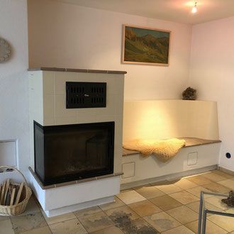 Weiße, ovale Badewanne auf einem Kieselbett, neben einem großen Fenster mit Blick ins Freie.