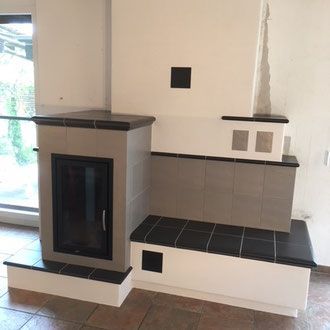 Schwarzes Metalltor mit gemauerten Säulen, die in eine graue Mauer eingelassen sind.