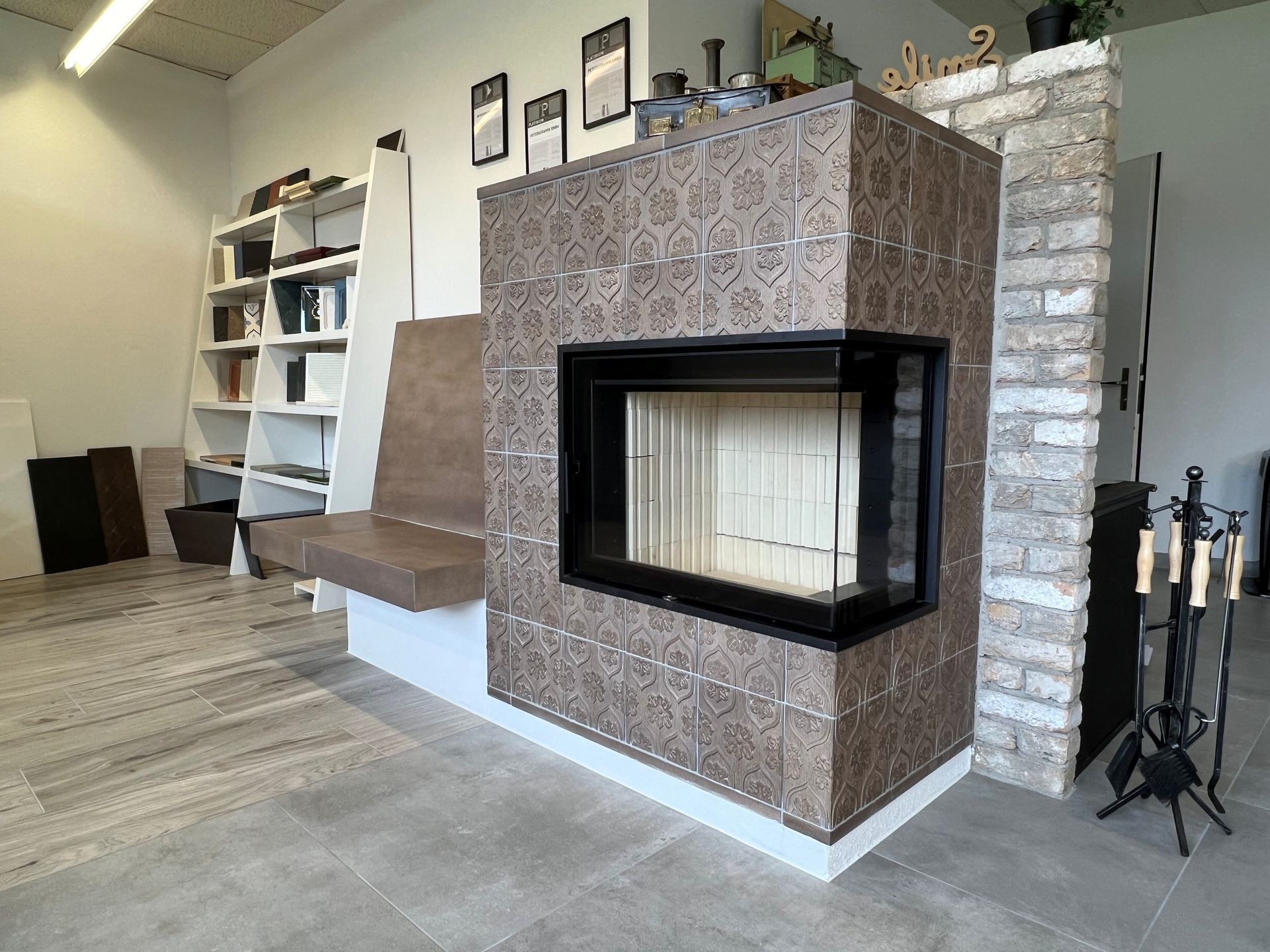 Modernes Wohnzimmer mit Kamin, grauem Fliesenboden und Glaswand zur Terrasse.