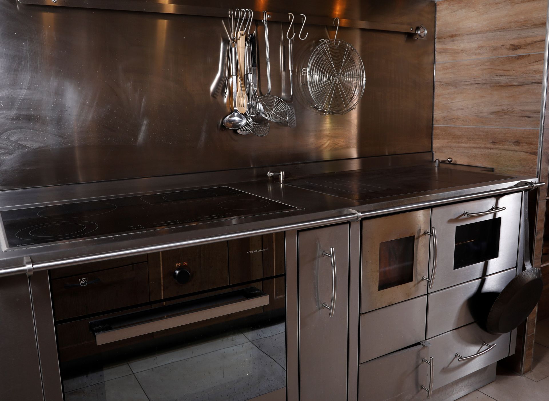 Küchenherd aus Edelstahl mit Backofen, Kochfeld und Hängevorrichtung für Küchenutensilien.