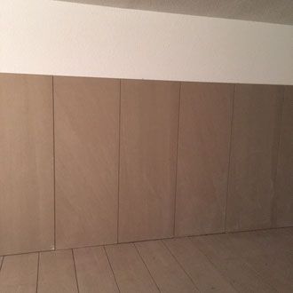 Braune Wandvertäfelung, darüber weiße Paneele. Darunter heller Holzboden.