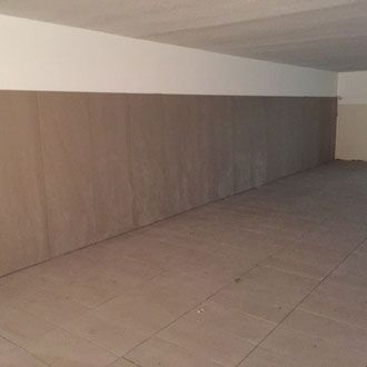 Leerer Raum mit beigefarbenen Fliesen an Boden und Wänden. Weiße obere Wand.