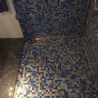 Duschkabine mit Wänden und Boden aus blauen, goldenen und grauen Mosaikfliesen.