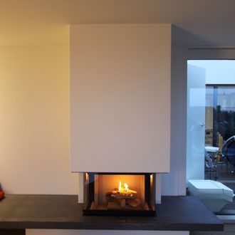 Moderner Kamin mit weißer Umrandung, brennendem Feuer und grauer Kaminplatte.