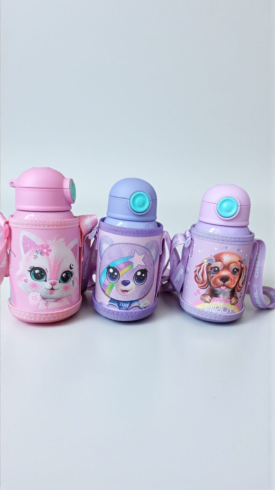 Tres coloridas botellas de agua con caras de animales y correas para transportarlas.