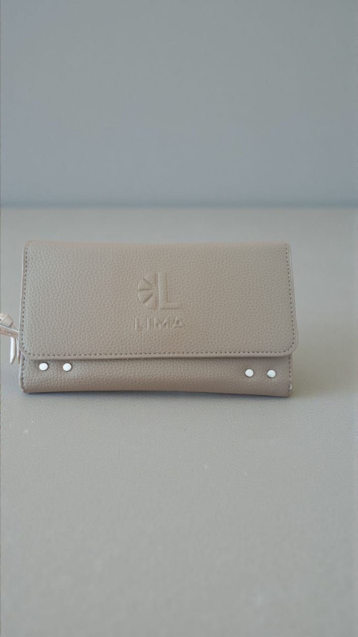 Cartera de piel color canela con cierre de solapa y tachuelas, sobre fondo gris.