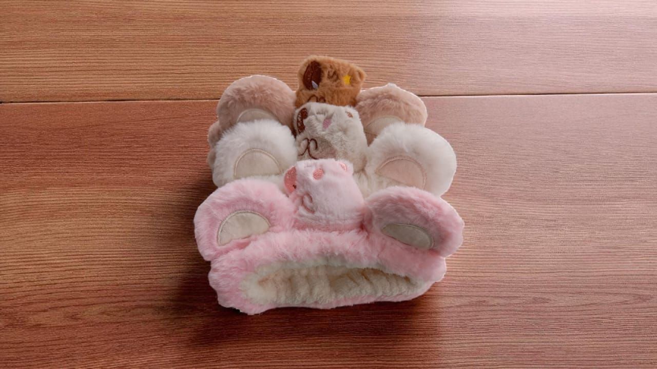 Montón de objetos de peluche con forma de animales en tonos rosa, beige y marrón sobre una superficie de madera.