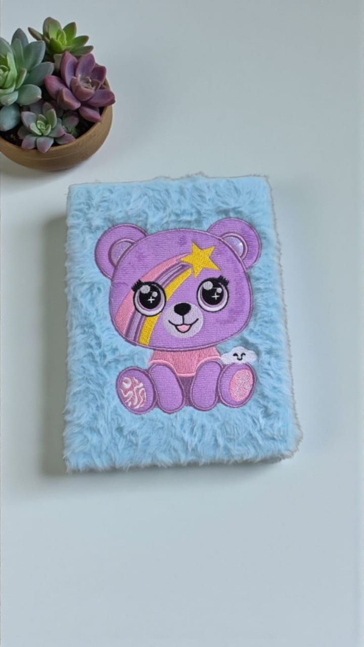 Libreta de peluche azul y morado con diseño de estrella fugaz y suculentas de fondo.