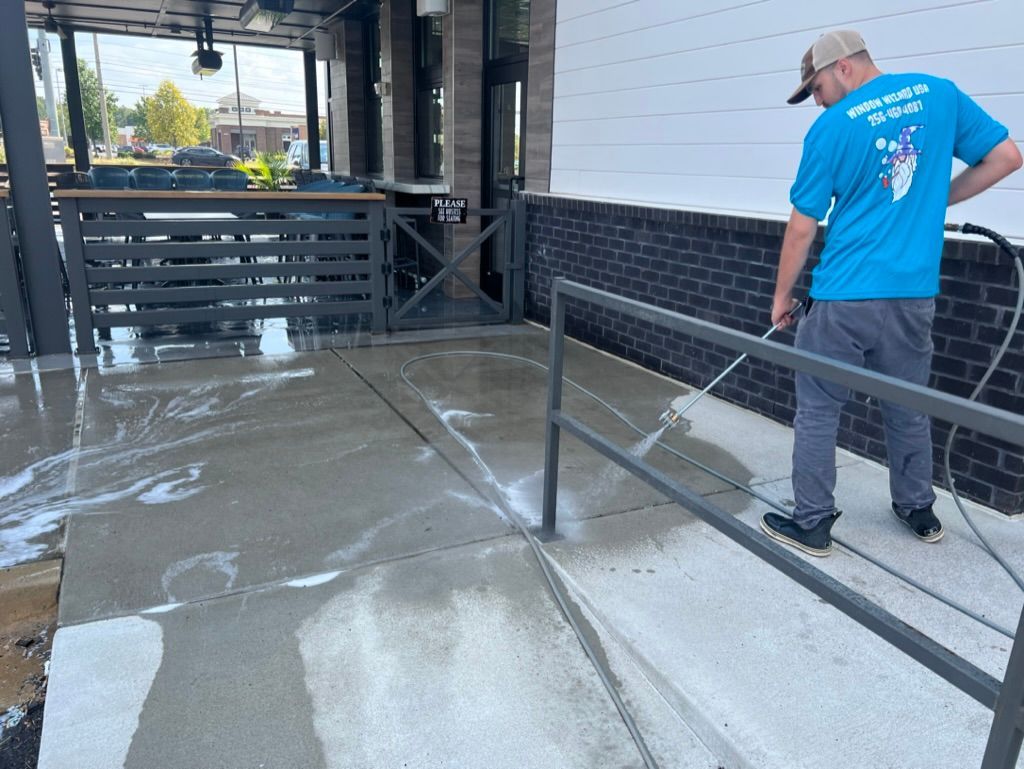 Worker in blue shirt and cap checking a wet concrete ramp beside a building Pressure Washing & Window Cleaning in Huntsville