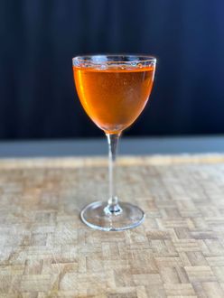 A glass of orange liquid is sitting on a wooden table.