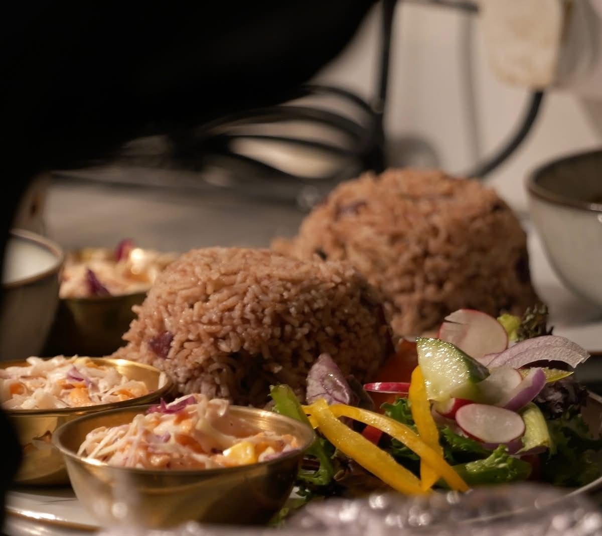 Plate of Caribbean food: rice, coleslaw, and a fresh salad.