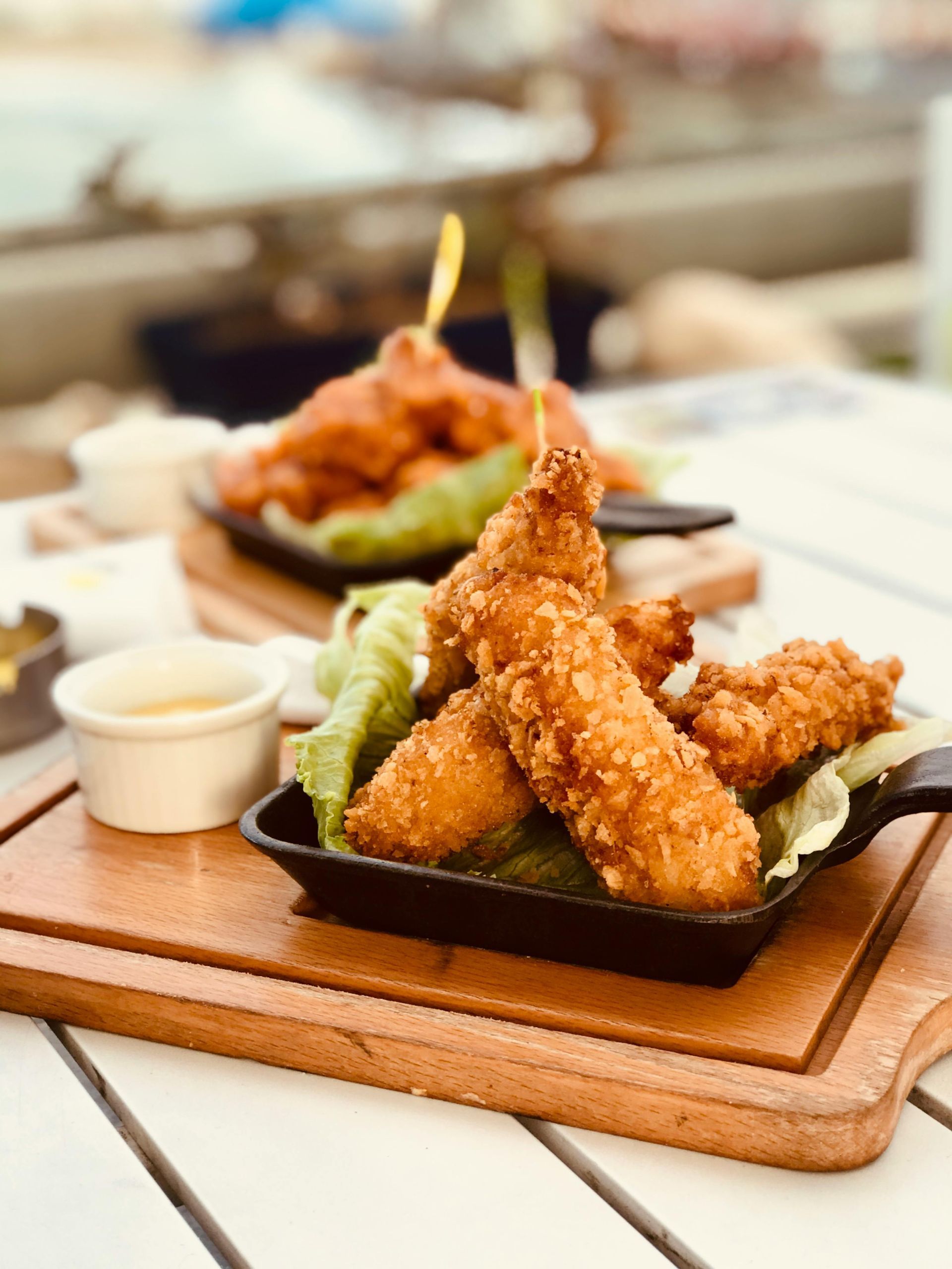 Fried chicken tenders on a wooden board with a dipping sauce