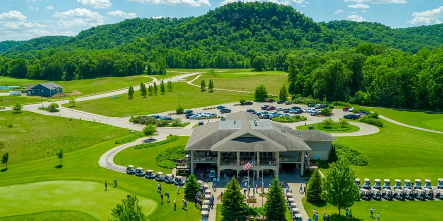 An aerial view of a golf course with mountains in the background.
