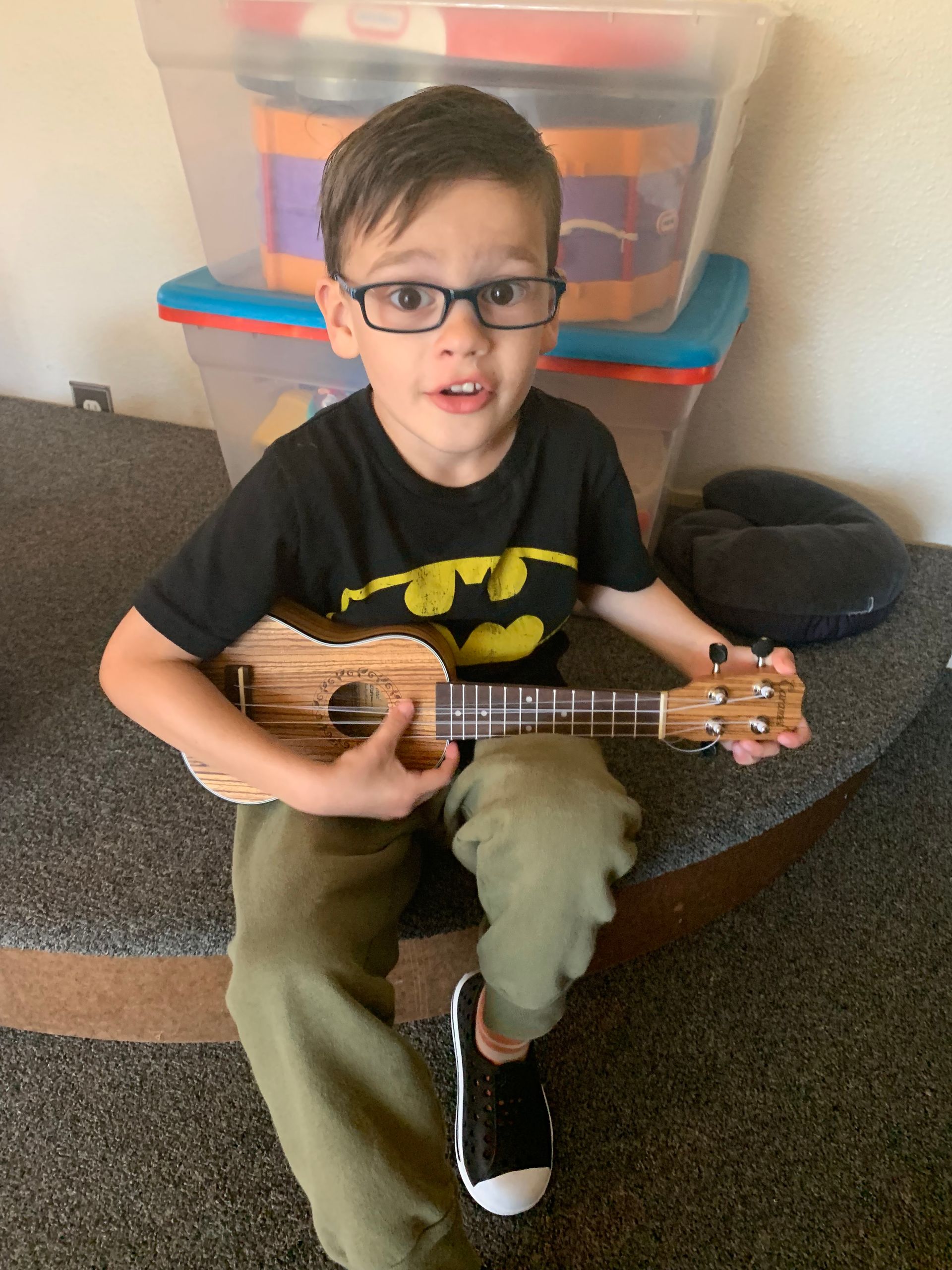 A young boy is sitting on a staircase playing a guitar.
