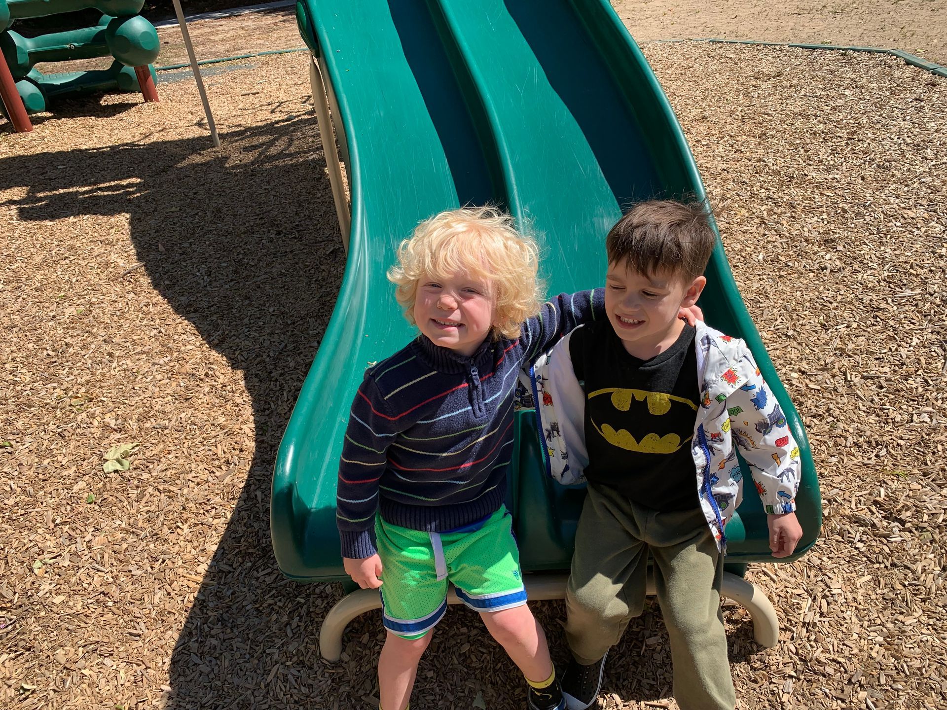 Two young boys are sitting on a slide at a playground.