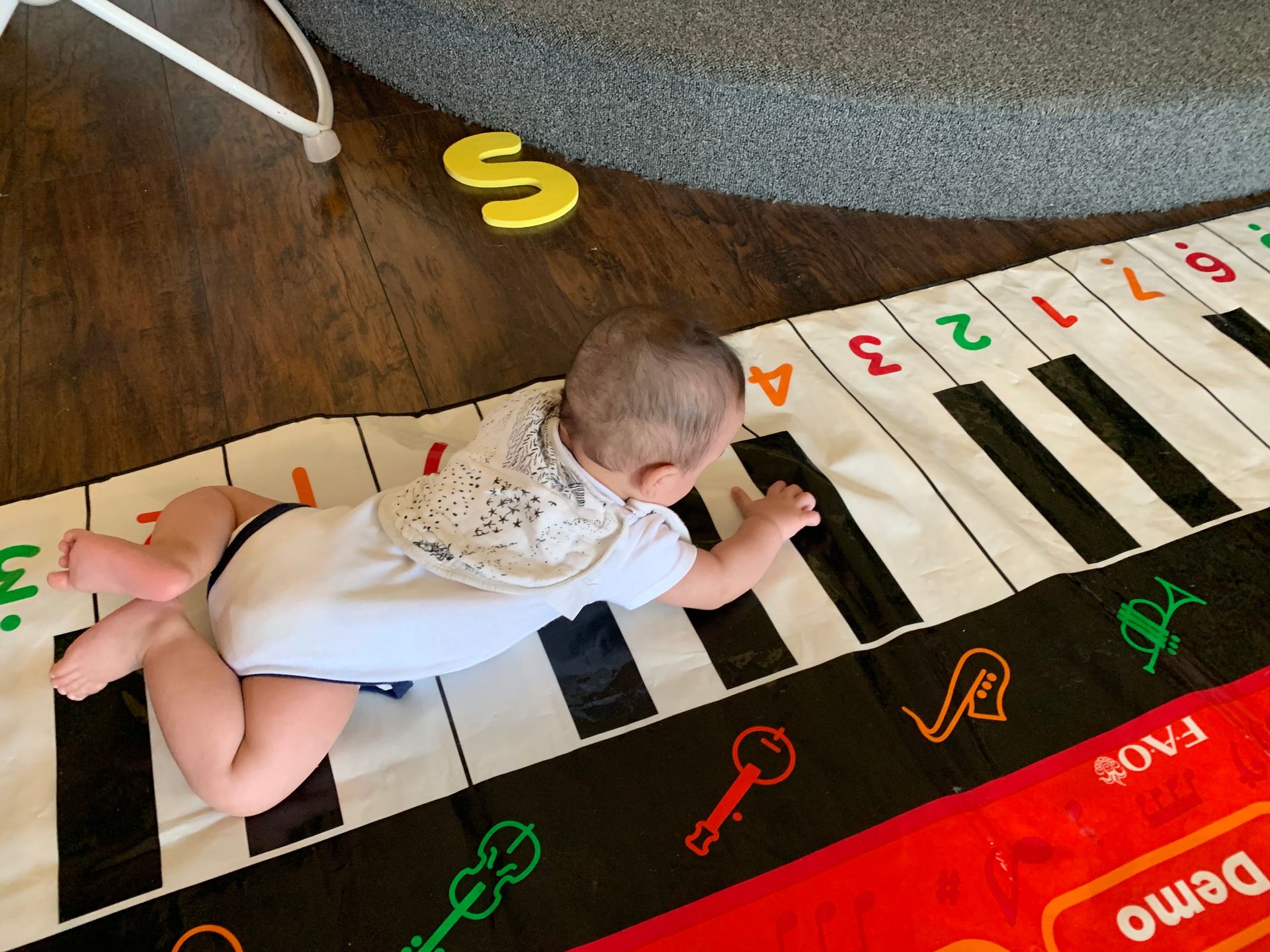 A baby is crawling on a piano keyboard mat