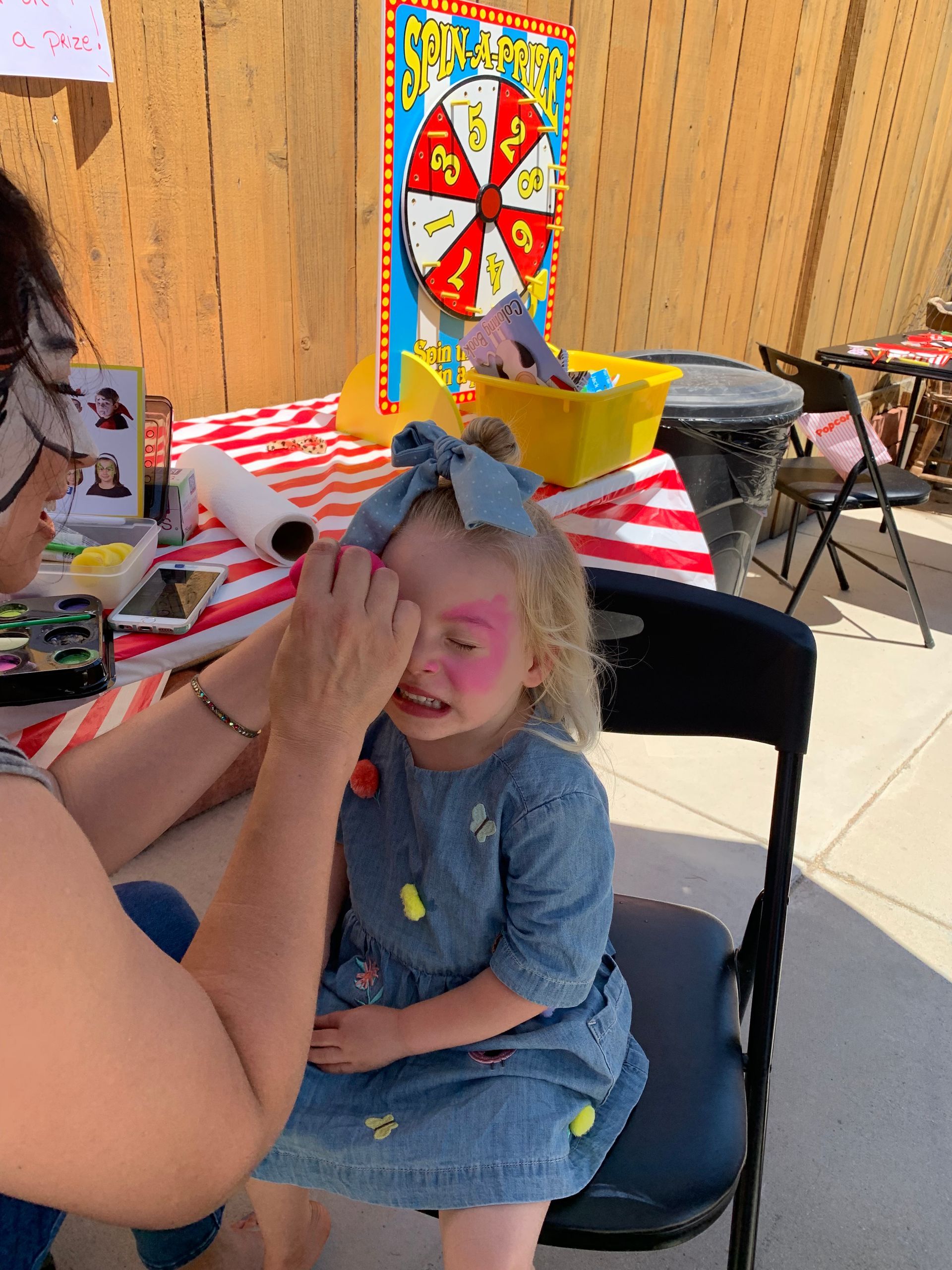 A little girl is getting her face painted by a woman