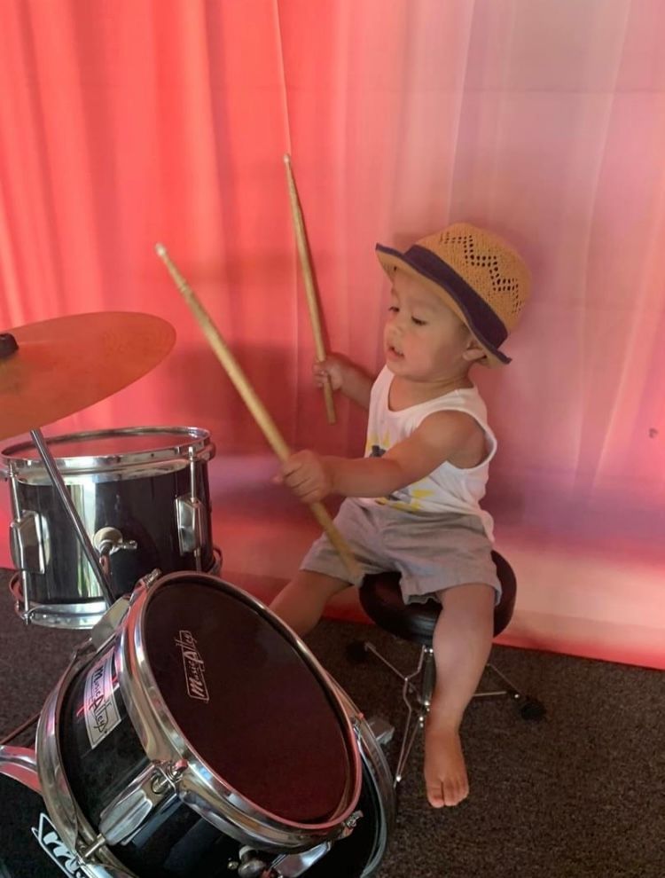 A baby is sitting on a drum set playing drums.