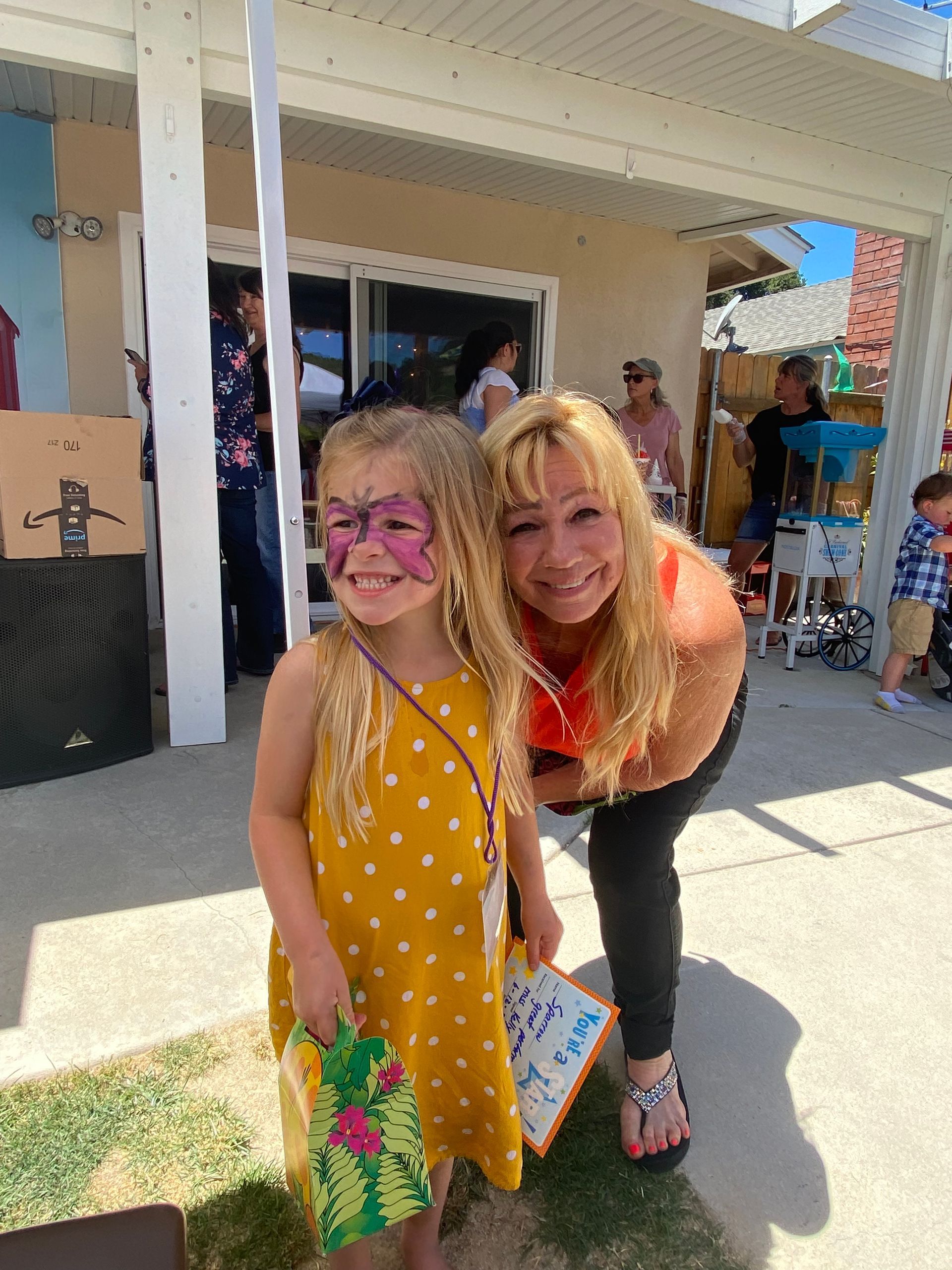 A woman is standing next to a little girl with her face painted.
