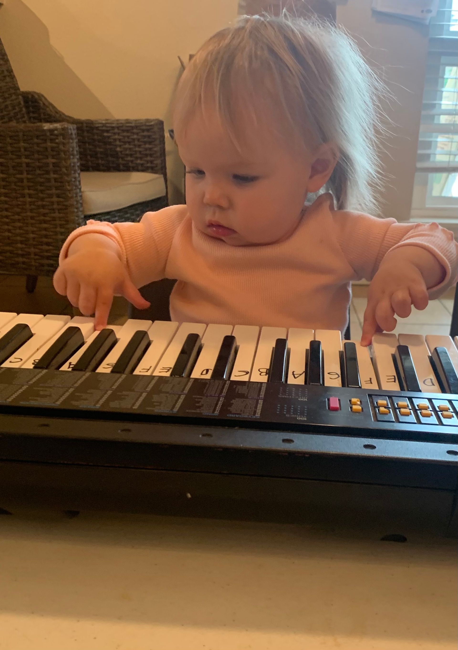 A baby is playing a keyboard on a table.