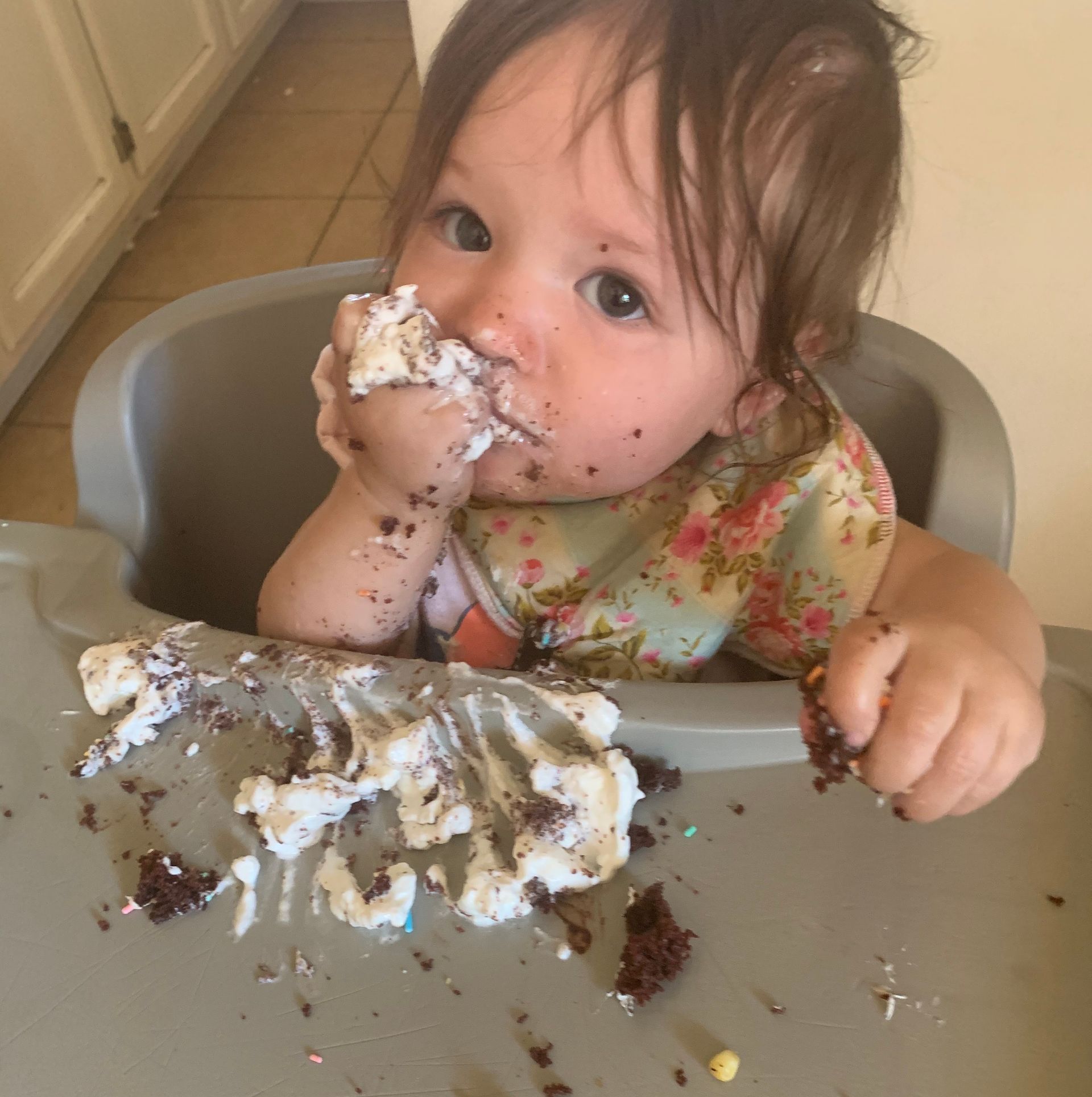 A baby is sitting in a high chair eating cake