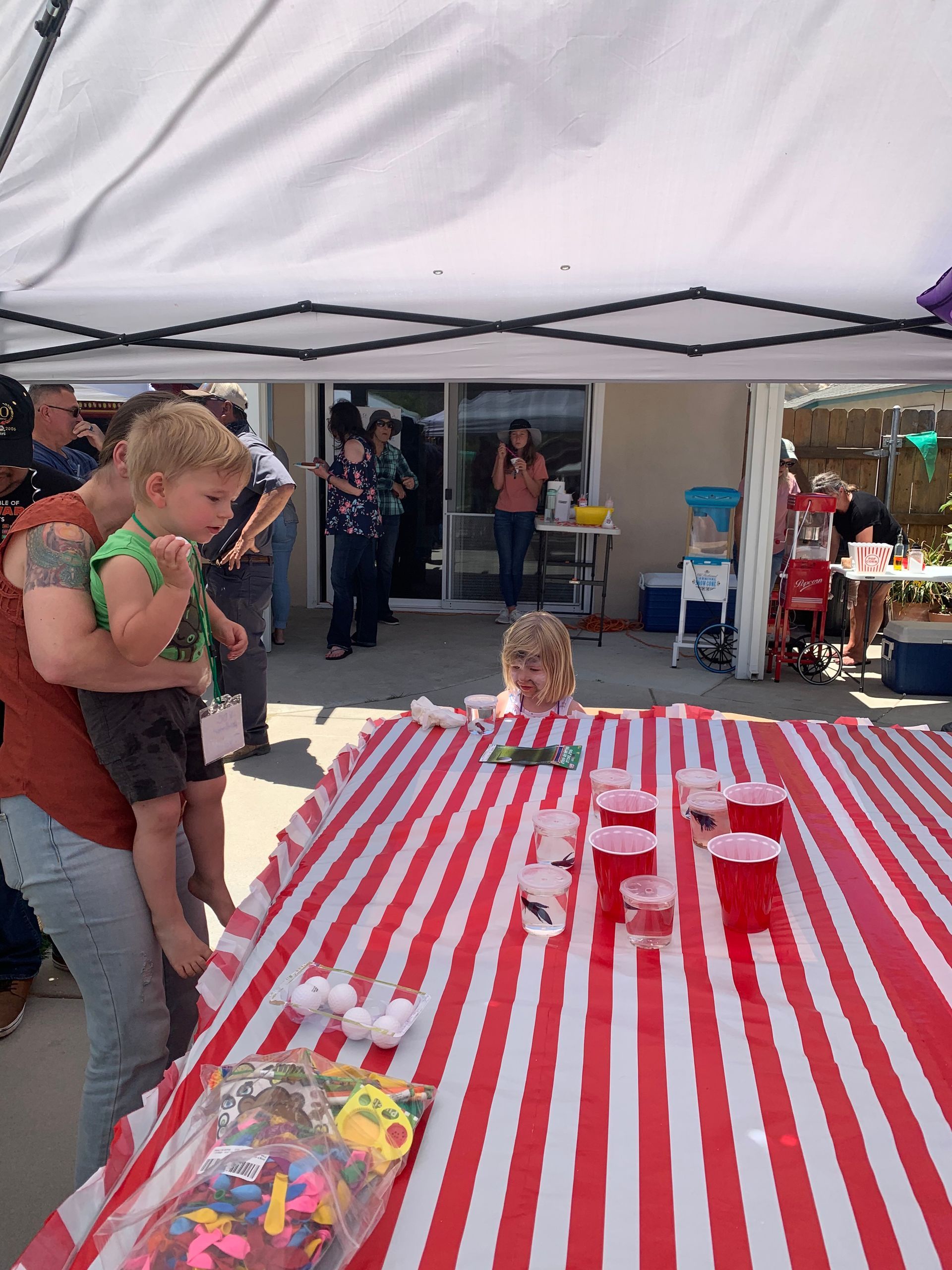 A group of people are standing around a table with balloons and cups on it.