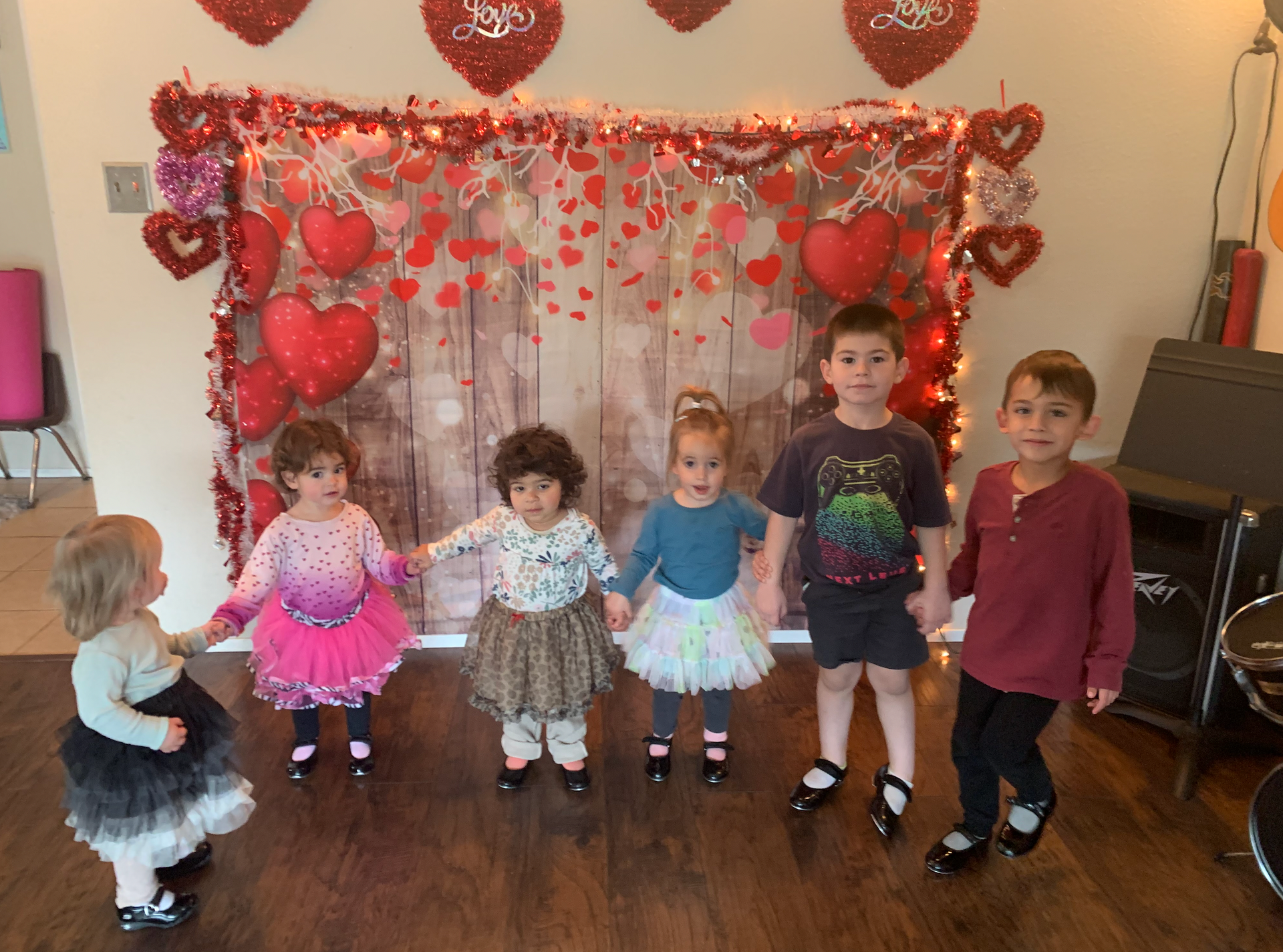 A group of children are standing in front of a wall with hearts on it.