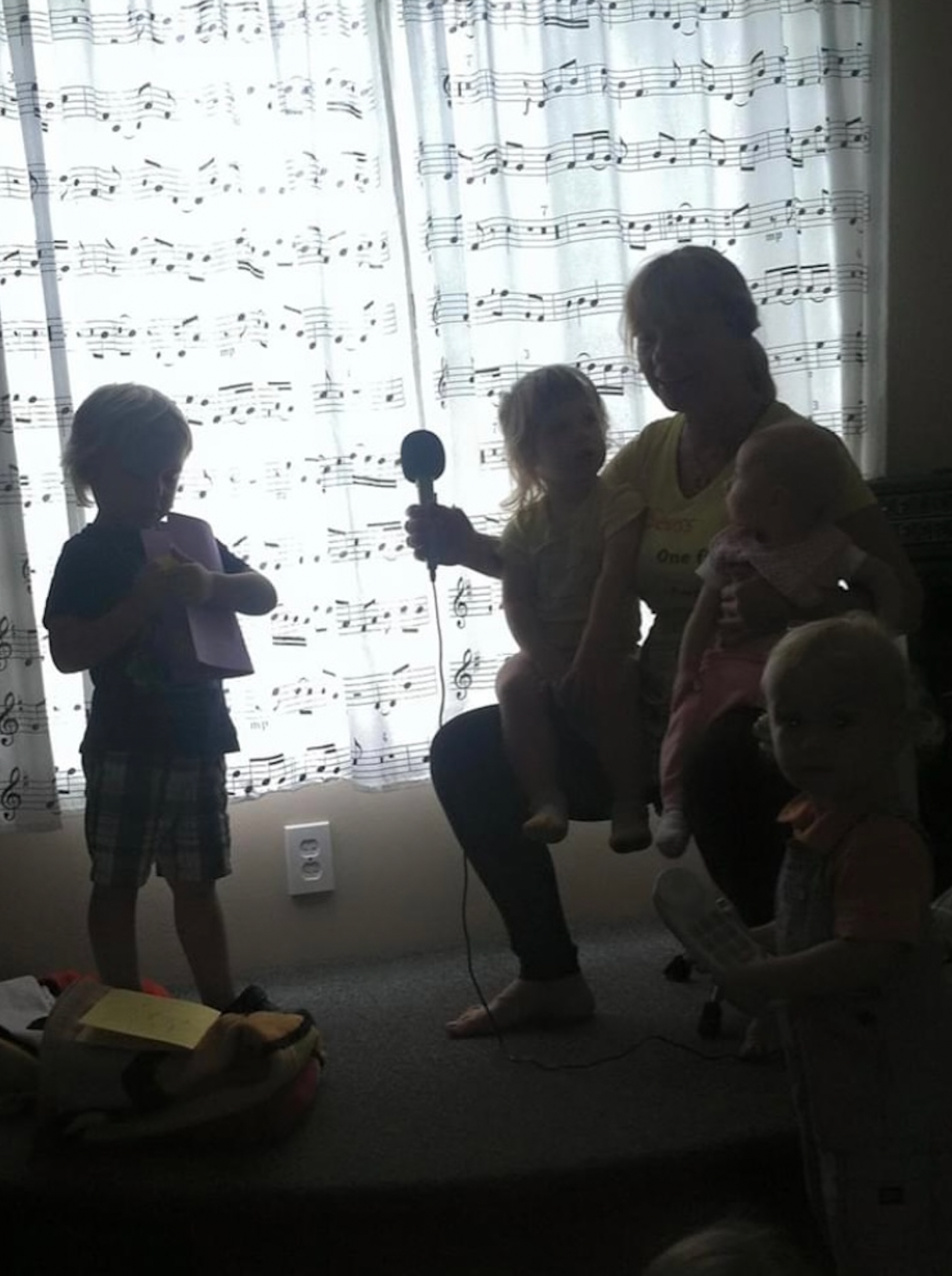A woman holds a microphone in front of a window with sheet music on it