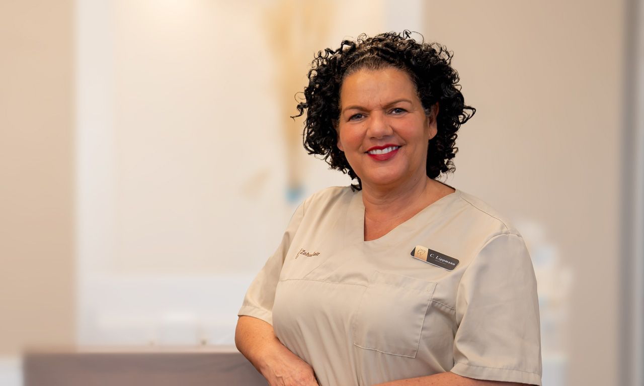 Zahnärztin Christina Lippmann steht in einer Zahnarztpraxis vor einem Zahnarztstuhl.