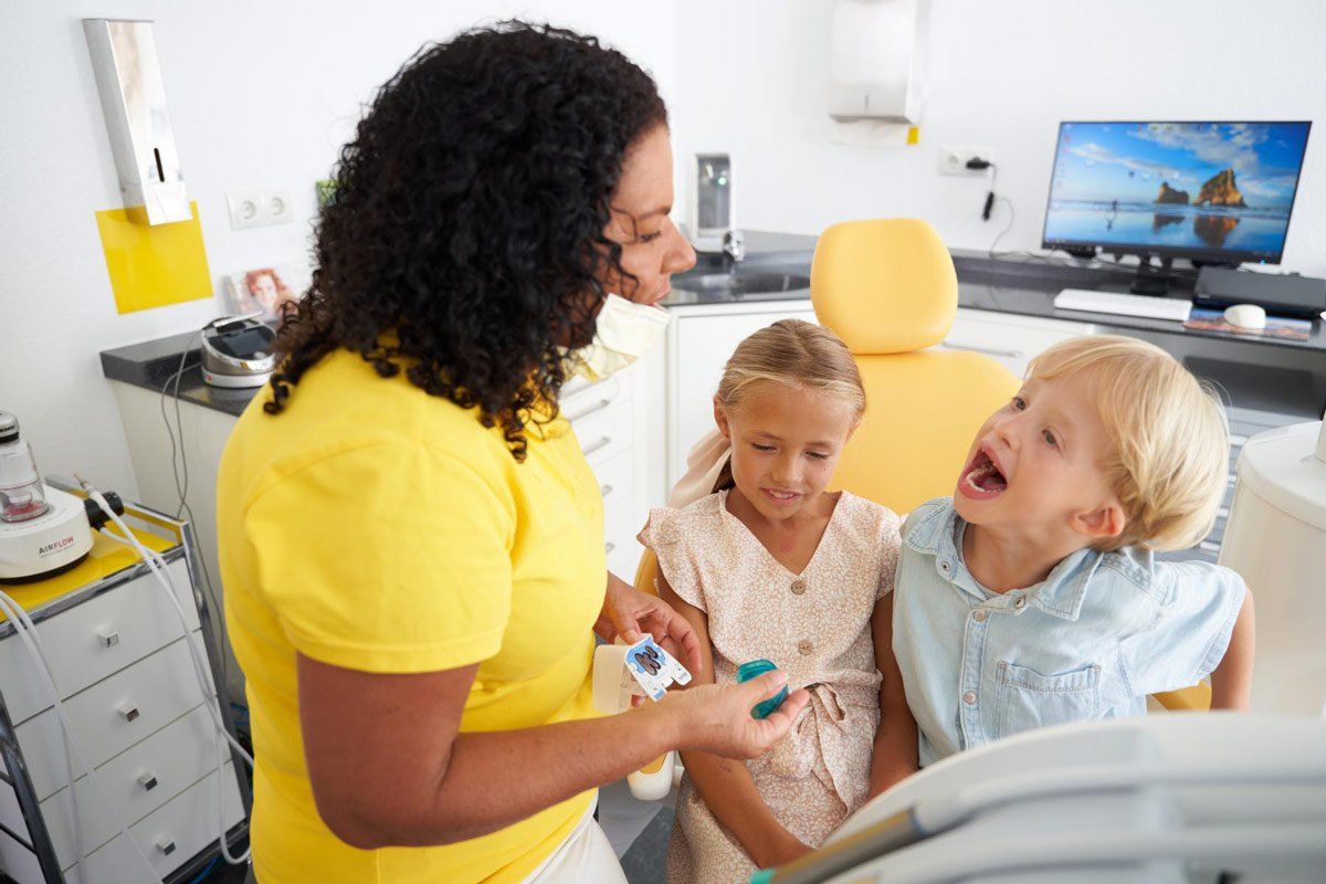 Zahnärztin Christina Lippmann spricht in einer Zahnarztpraxis mit zwei kleinen Mädchen.