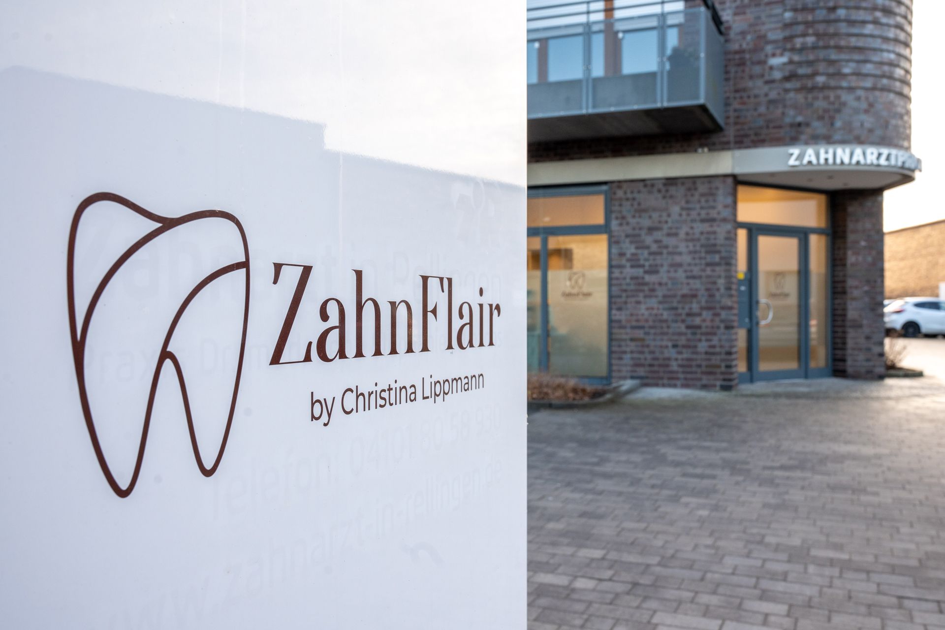 Ein Schild mit dem Logo ZahnFlair by Christina Lippmann vor der zahnarztPraxis